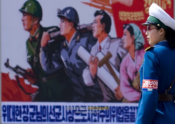 North Korean female traffic officer in front of a propaganda billboard in the street, Pyongan Province, Pyongyang, North Korea