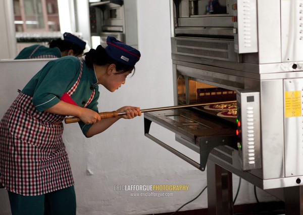 North Korean pizzeria cook putting a pizza in the oven in an italian restaurant, Pyongan Province, Pyongyang, North Korea