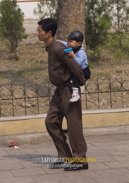 North Korean father walking in the street with his son on his back, Pyongan Province, Pyongyang, North Korea