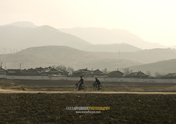 North Korean men cycling in the countryside, South Pyongan Province, Nampo, North Korea