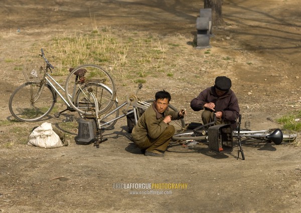 North Korean men repairing bicycles along the road, South Pyongan Province, Nampo, North Korea