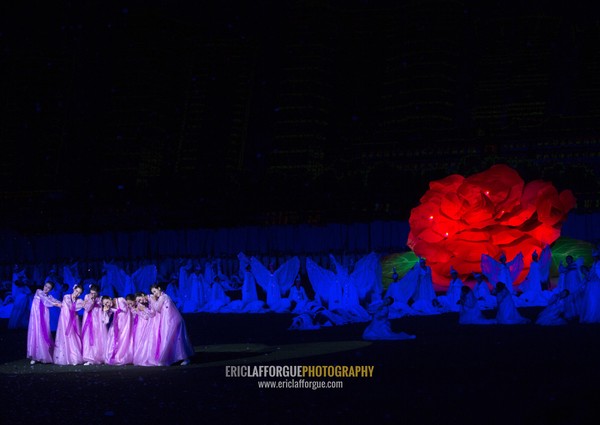 North Korean women dancing in front of a giant Kimilsungia flower during the Arirang mass games in may day stadium, Pyongan Province, Pyongyang, North Korea