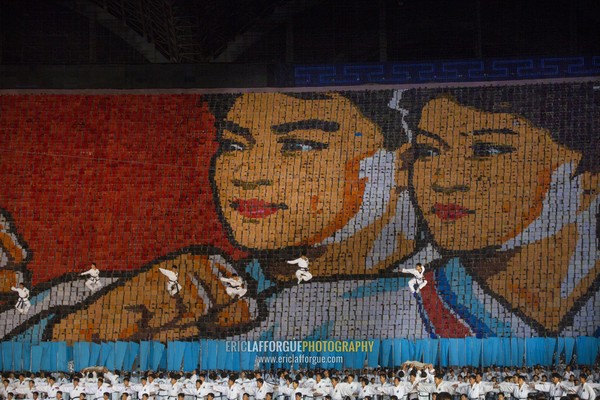 Gymnasts jumping in front of taekwando fighters made by children pixels holding up colored boards during Arirang mass games, Pyongan Province, Pyongyang, North Korea