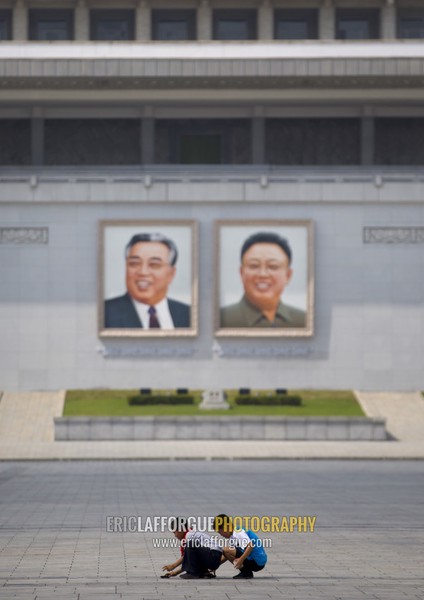 North Korean boys playing in front of Kim il Sung and Kim Jong il giant portraits on Kim il Sung square, Pyongan Province, Pyongyang, North Korea