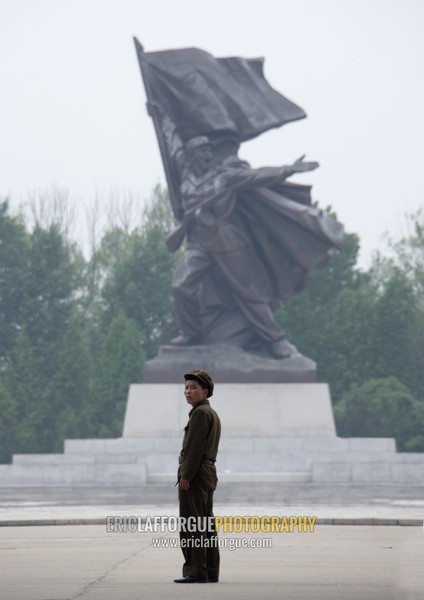 North Korean man standing in front of a sioldier statue, Pyongan Province, Pyongyang, North Korea