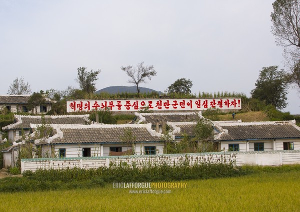 North Korean propaganda billboard in front of houses in a village, South Hamgyong Province, Hamhung, North Korea