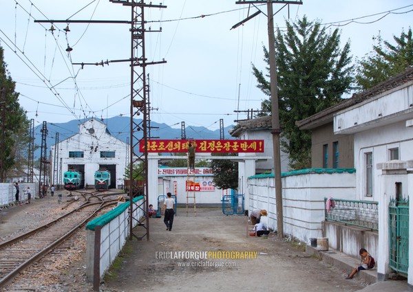 Train station and garage in a village with the slogan long live general Kim jong-un, The sun of songun joseon, South Hamgyong Province, Hamhung, North Korea