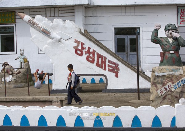 North Korean pioneer passing in front of a missile monument in a school, South Hamgyong Province, Hamhung, North Korea