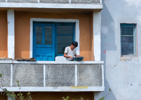 North Korean man washing clothes on his balcony, South Hamgyong Province, Hamhung, North Korea