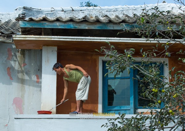 North Korean man painting his house, South Hamgyong Province, Hamhung, North Korea