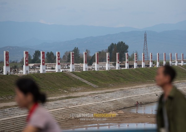 North Korean people passing in front of propaganda billboards, South Hamgyong Province, Hamhung, North Korea