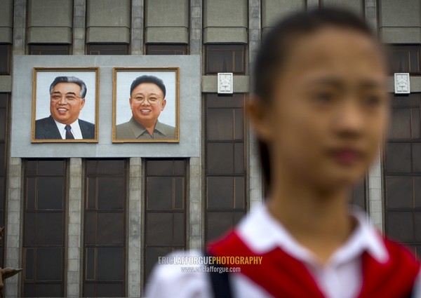 Pioneer girl in Mangyongdae children's palace in front of the portraits of the Dear Leaders, Pyongan Province, Pyongyang, North Korea