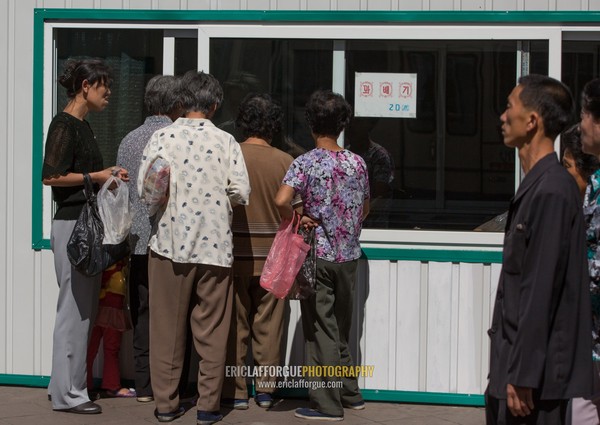 North Korean people queueing to buy some food in a shop in the street, Pyongan Province, Pyongyang, North Korea