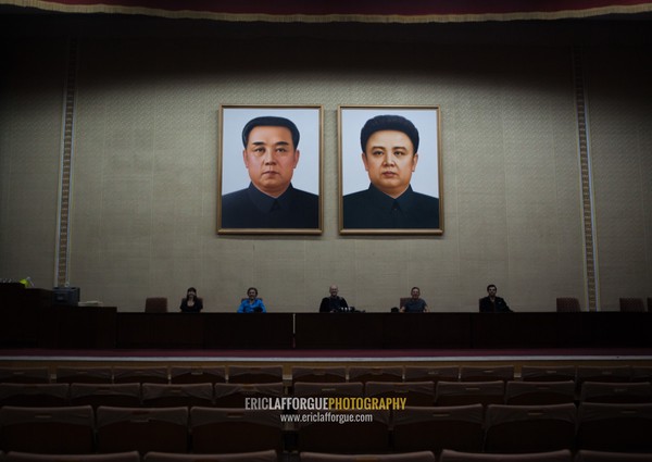 Tourists posing below the portraits of the Leaders in a conference room of the Grand people's study house, Pyongan Province, Pyongyang, North Korea