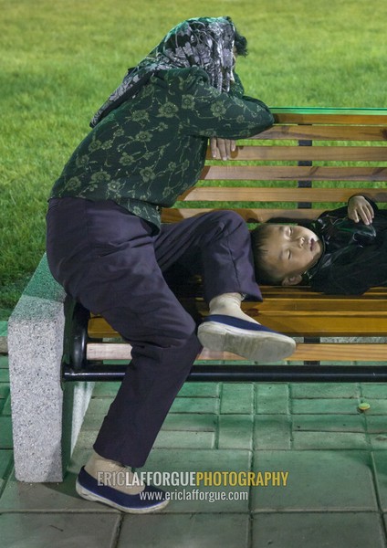 North Korean mother and her son sleeping on a bench in a park at night, Pyongan Province, Pyongyang, North Korea