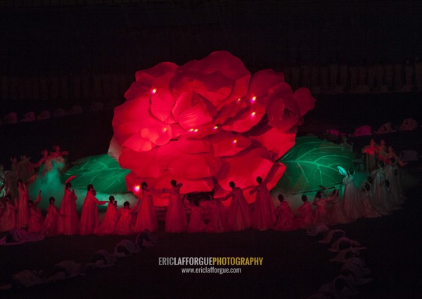 North Korean women dancing in front of a giant Kimilsungia flower during the Arirang mass games in may day stadium, Pyongan Province, Pyongyang, North Korea