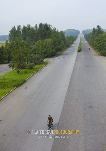 North Korean man riding a bicycle on an empty highway, North Hwanghae Province, Kaesong, North Korea